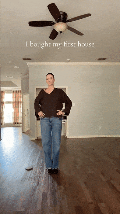 Gen Z woman stands confidently in empty living room celebrating first home purchase and financial independence milestone.