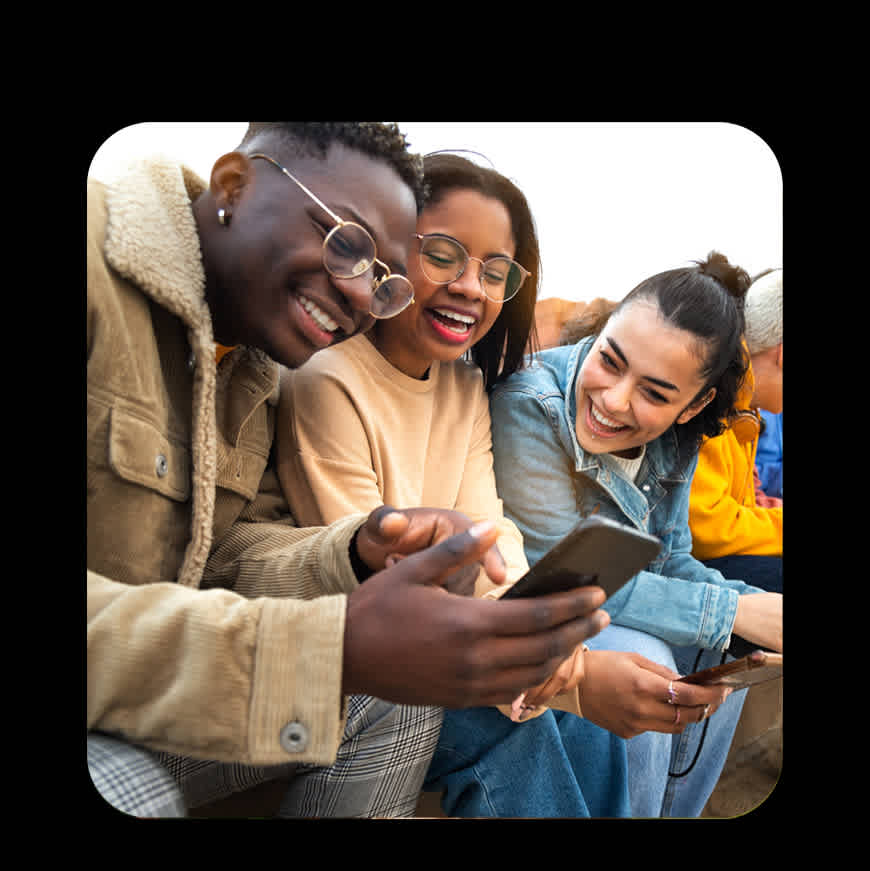 A group of three young Gen Z friends smile at phone together