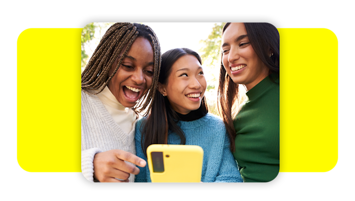 Group of friends laughing at something on their cell phone.