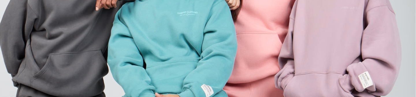 Torso-level close-up of four people wearing Comfrt hoodies in a variety of colors.