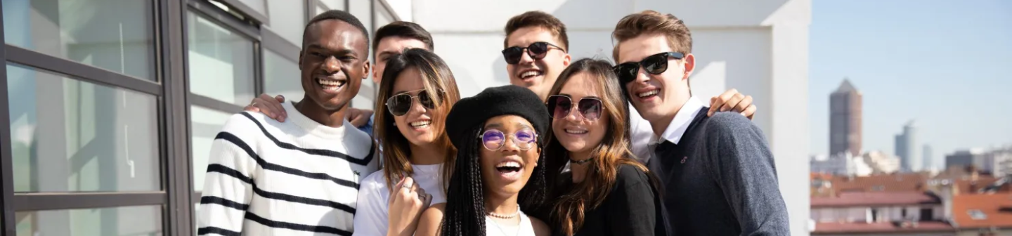 A diverse group of young, smiling college students posing together outside.